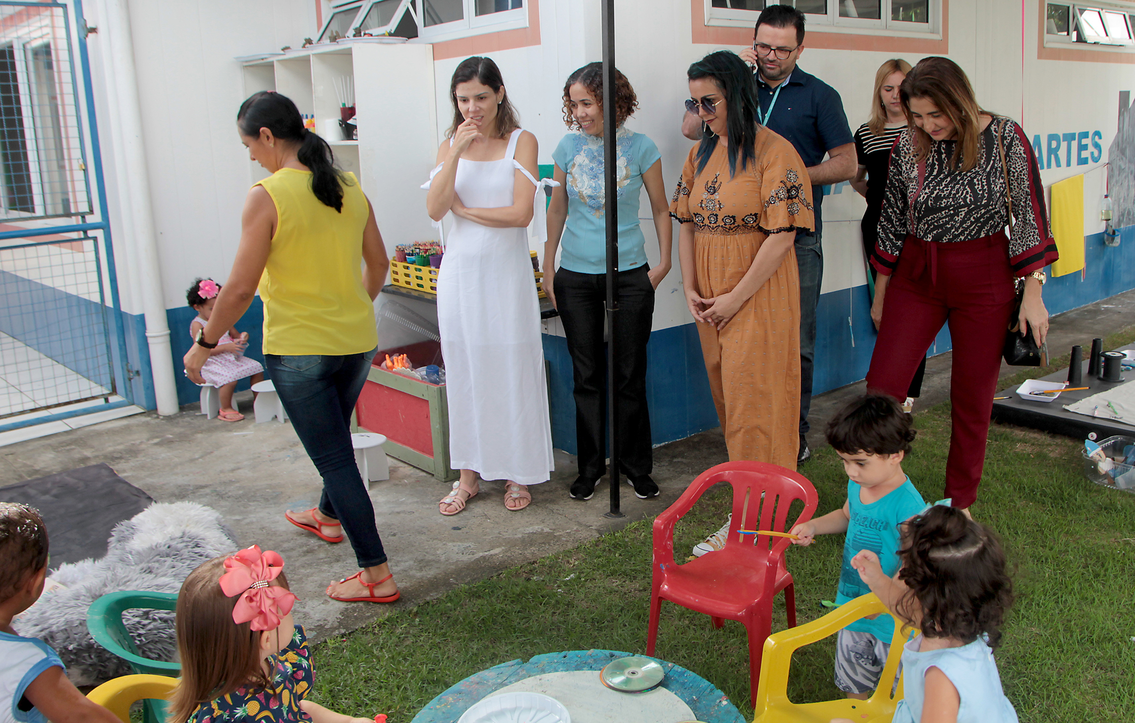 várias pessoas em pé num pátio de uma creche